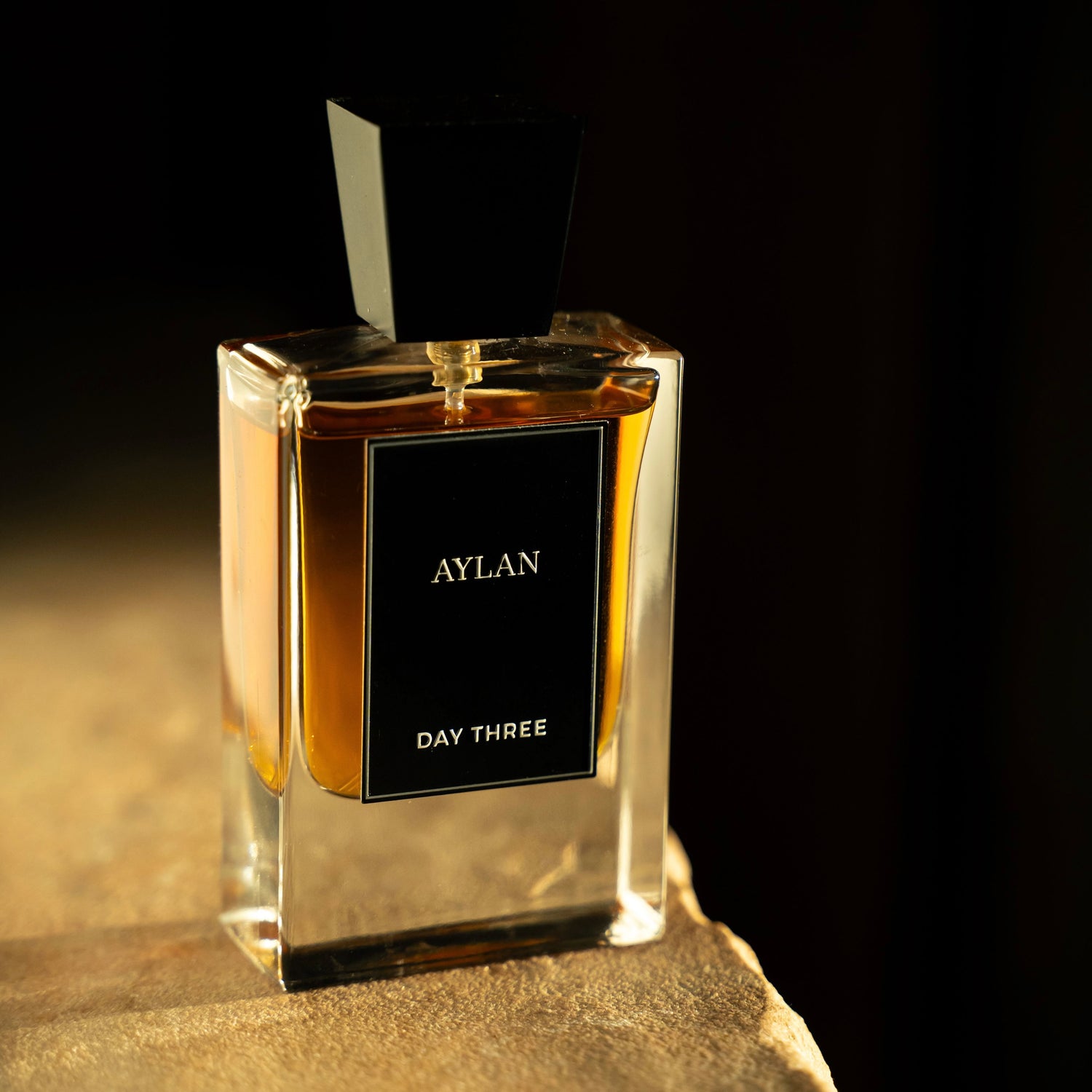 Perfume bottle labeled 'AYLAN DAY THREE' on a dark background