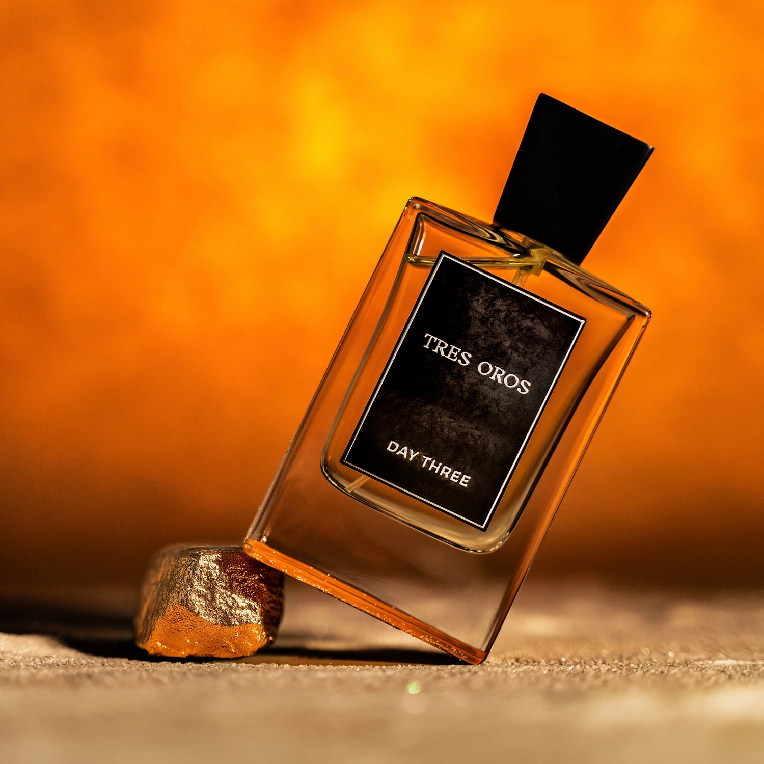 Perfume bottle labeled 'Tres Oros Day Three' on a warm-toned background